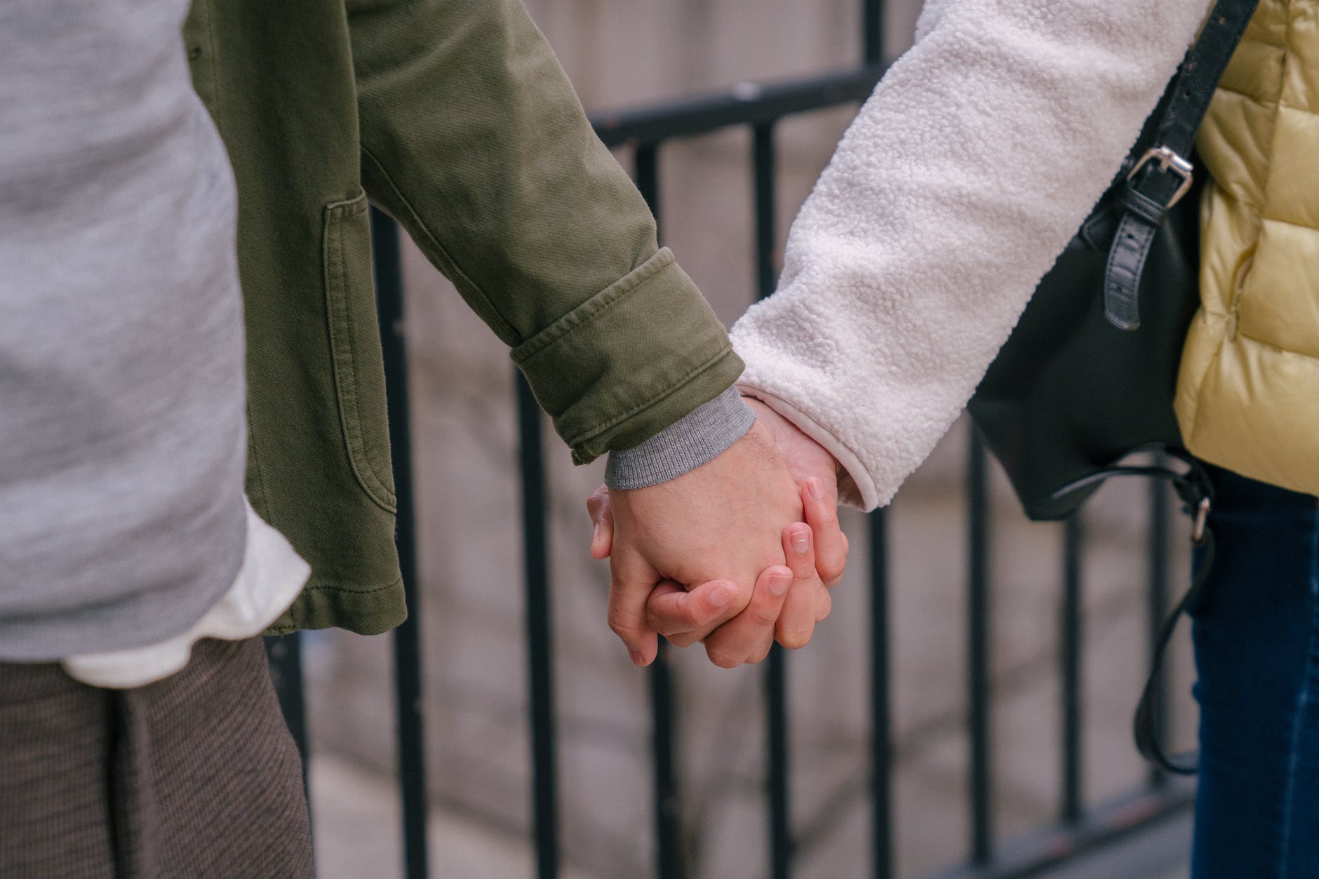 couple standing near metal fence and holding hands together in relationship