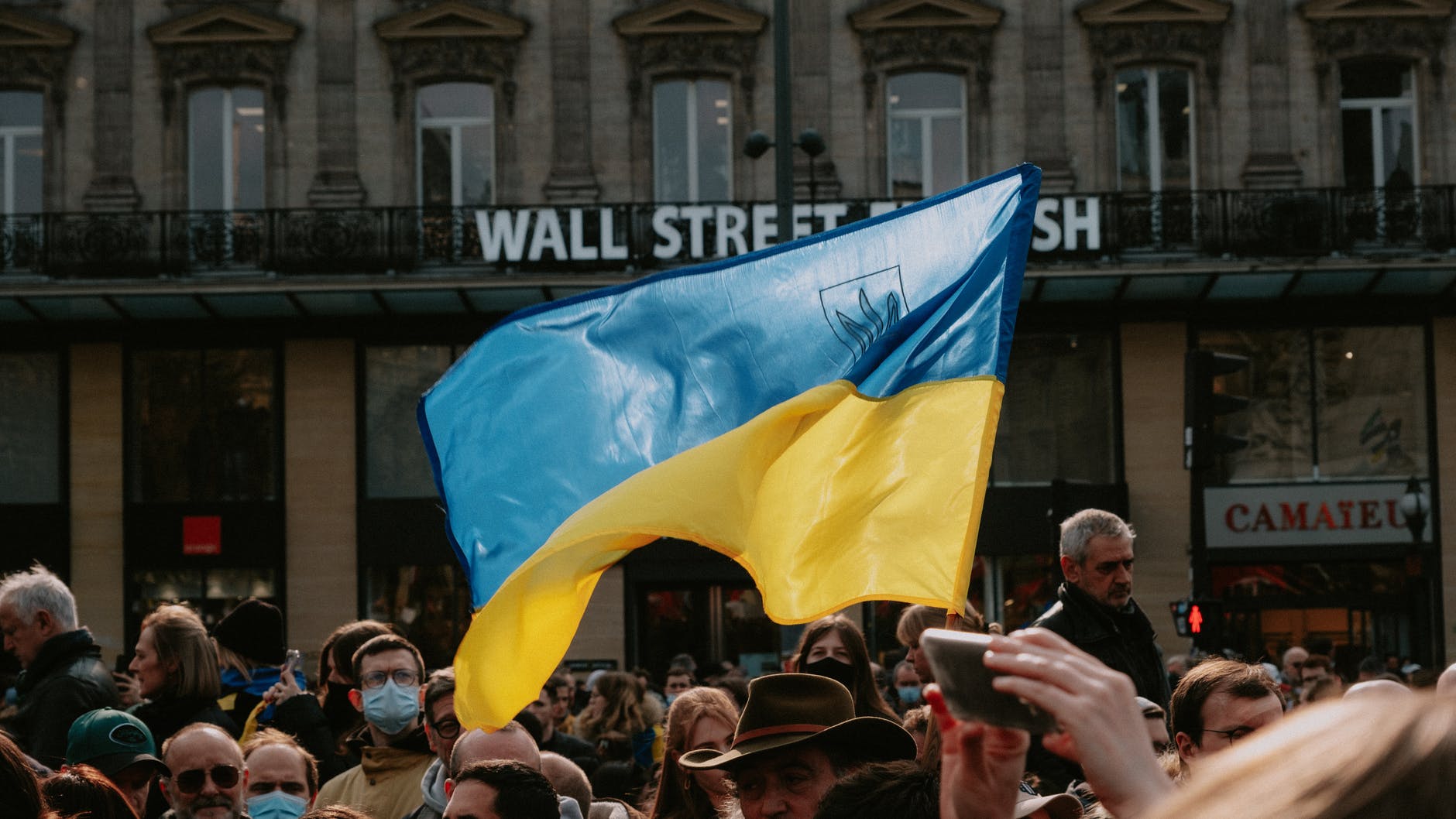 stories of war blue and yellow ukrainian flag waving above crowd of people