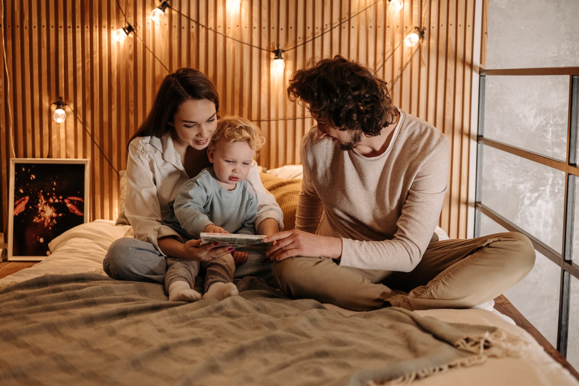 family sitting on the bed while looking at a book