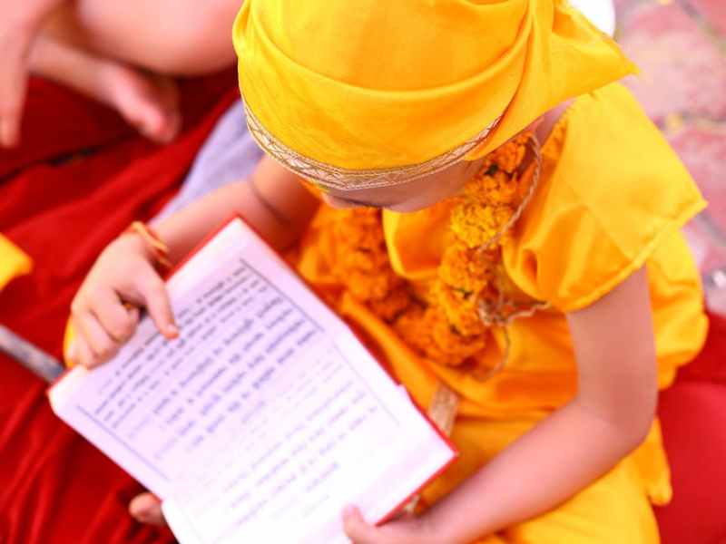 child in traditional attire reading a book outdoors