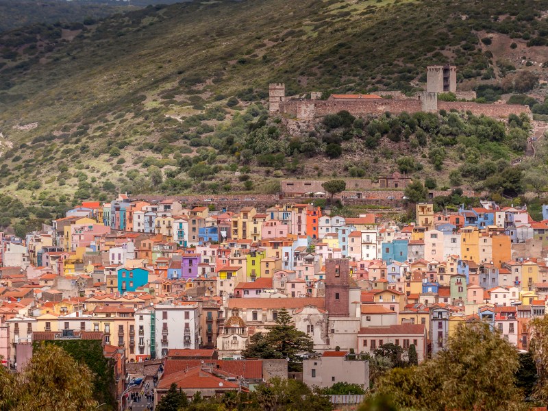 Veduta panoramica di Bosa, borgo colorato della Sardegna occidentale, con il Castello dei Malaspina e le case multicolori affacciate sul fiume Temo.
