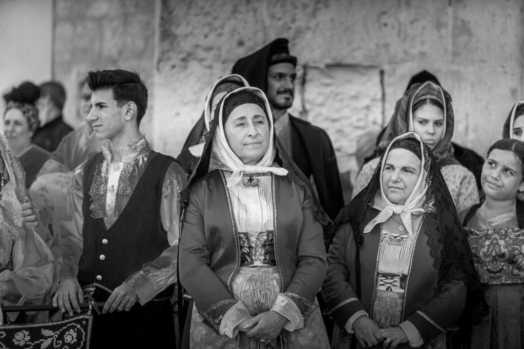 Gruppo di persone in costumi tradizionali sardi durante la Sagra de Sa Panada, in bianco e nero.