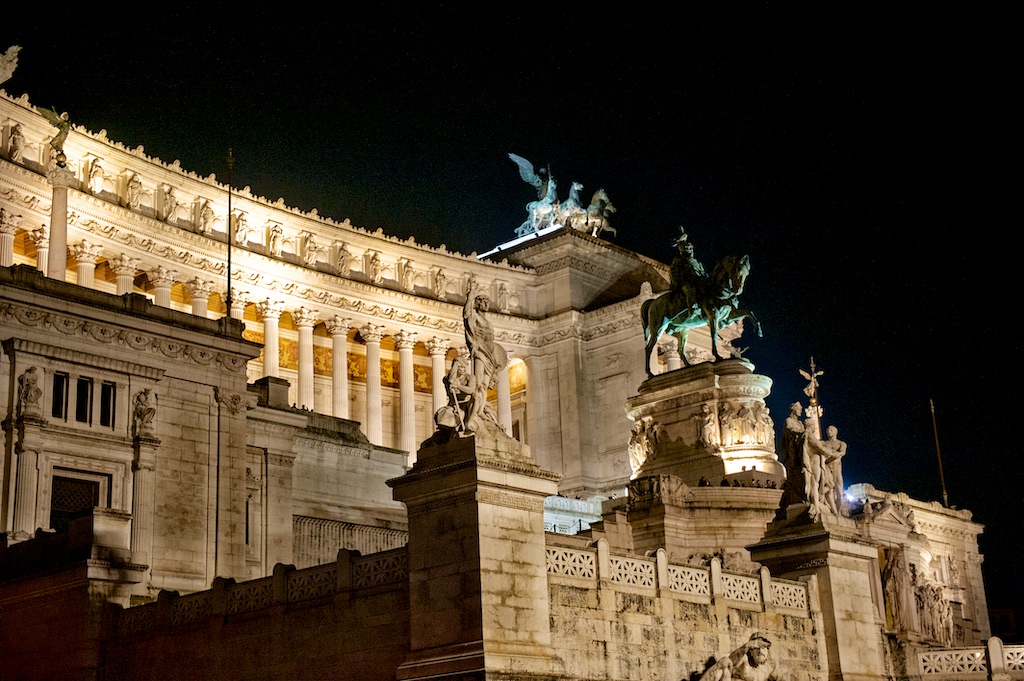 Veduta panoramica notturna della bellezza eterna di Roma, tra Colosseo, Cupola di San Pietro e le strade di Trastevere.