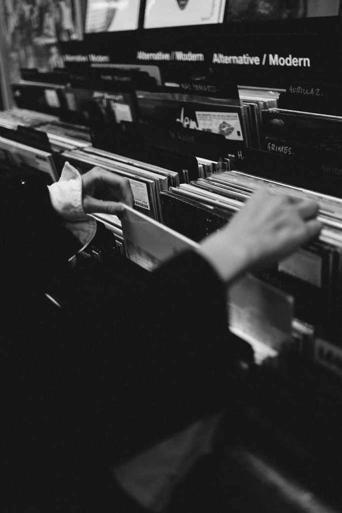 grayscale photo of a person s hand buying vinyl records