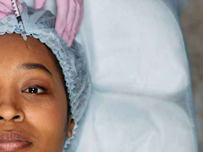 woman lying down receives forehead botox