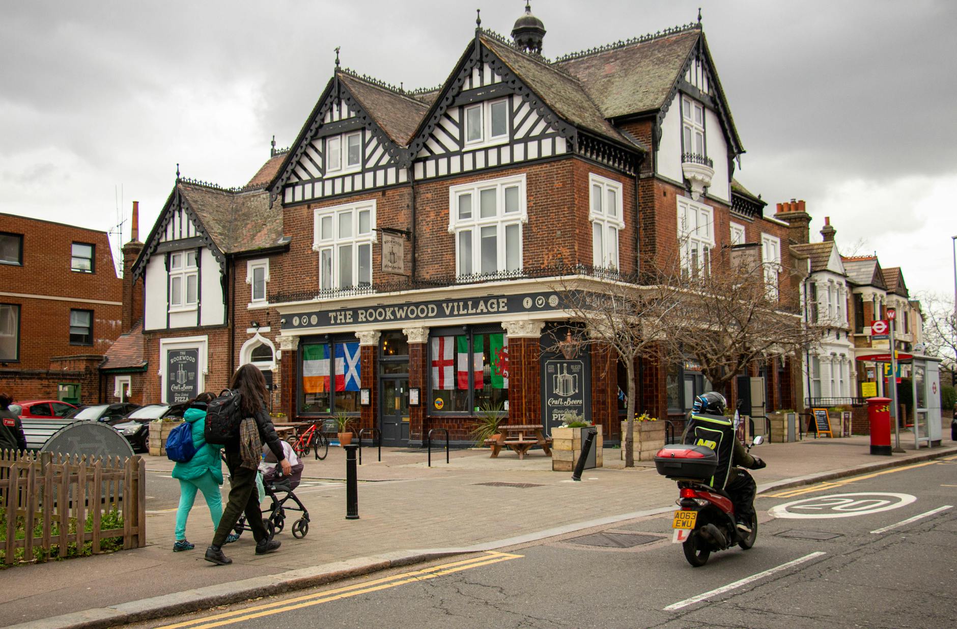 people walking on the sidewalk near the building in Wimbledon a typical slow cities
