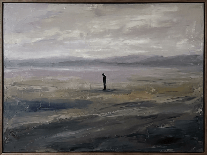Silhouette of a person standing alone in a vast, misty landscape with muted colors